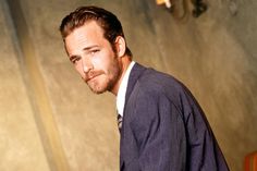 a man with a goatee and beard standing in front of a wall looking at the camera