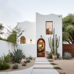 a white stucco house with cactus and succulents