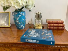 a book sitting on top of a wooden table next to a vase filled with flowers