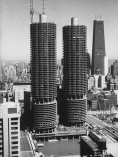 black and white photograph of two skyscrapers in the middle of a city with tall buildings