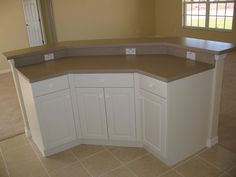 an empty kitchen with white cabinets and beige counter tops in the middle of the room