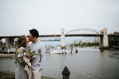 a man and woman standing next to each other near the water