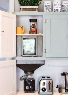 an open cabinet in the corner of a kitchen with coffee maker and toaster on it