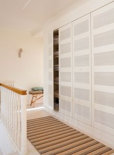 a hallway with white walls and carpeted flooring next to a wooden banister