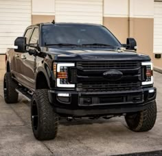 a black pickup truck parked in front of a building with two large tires on it