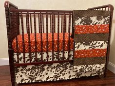 a baby crib with an orange and brown blanket on it's bedding