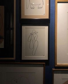 three framed drawings hang on the wall next to each other in front of blue walls