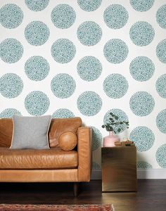 a brown leather couch sitting in front of a wall with blue and white circles on it