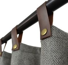 a pair of brown leather handles hang from a gray and white checkered fabric curtain