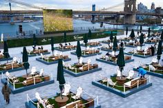 an outdoor seating area with tables and umbrellas in front of a bridge over water