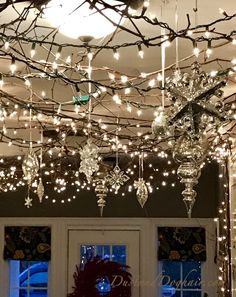 christmas lights are hanging from the ceiling in front of a white door and windows with wreaths on them