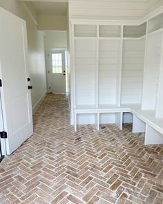 an empty room with brick flooring and white shelves on either side of the door