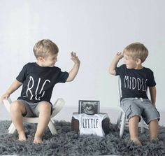 two young boys sitting on chairs in front of a white wall