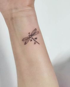 a small dragonfly tattoo on the wrist