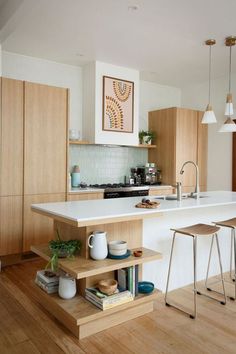 a kitchen with wooden flooring and white counter tops next to a bar stools