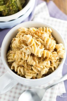 a white bowl filled with macaroni and cheese on top of a purple table cloth