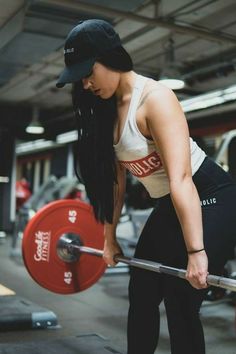 a woman lifting a barbell in a gym