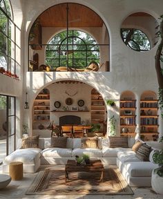 a living room filled with white furniture and lots of bookshelves on the wall