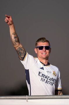 a man with tattoos on his arm and arms raised in the air, wearing sunglasses