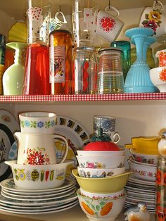 the shelves are filled with colorful dishes and cups