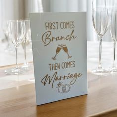 a sign that says first comes brunch then comes marriage with champagne glasses in the background