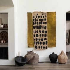 three black and white vases sitting on top of a wooden floor next to a wall