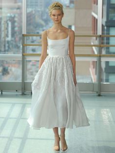 a model walks down the runway in a white dress