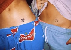 two women with matching tattoos on their stomachs, one is holding a cell phone