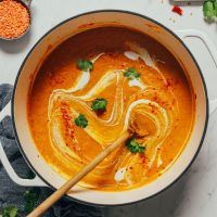 an overhead view of a bowl of soup with noodles and carrots on the side