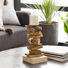 a stack of logs sitting on top of a table next to a book and candle