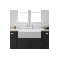 a white kitchen sink sitting under a window next to a counter top with gold trim