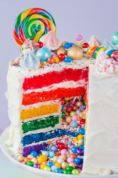 a rainbow cake with white frosting and lots of candies