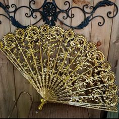 an ornate gold fan sitting on top of a wooden table next to a metal rack