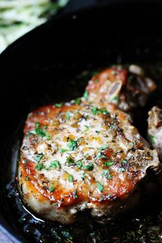 a piece of meat in a skillet with some parsley on the top,