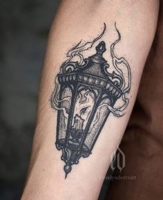 a man's arm with a black and white tattoo of a lantern on it