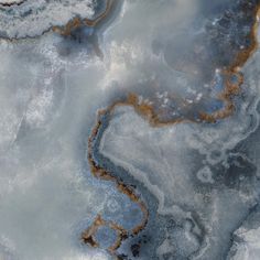 an aerial view of water and ice with brown streaks on the top, blue sky in the background