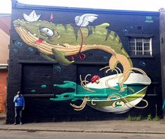 a man standing in front of a large mural on the side of a black building