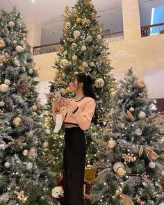 a woman standing in front of christmas trees