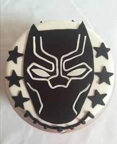 a cake decorated with black and white icing depicting a mask on top of stars