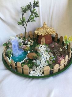 a miniature garden is displayed on a green platter with rocks and plants in it