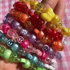 there are many different colored beads in the palm of a person's hand on a pink checkered table cloth