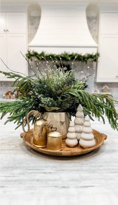 a christmas centerpiece with evergreen, pine cones and gold ornaments on a wooden tray