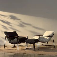 two black and white chairs sitting next to each other on a tile floor in front of a wall