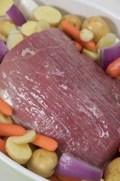 meat and vegetables in a white bowl on a table