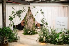 an indoor wedding ceremony with greenery and white drapes