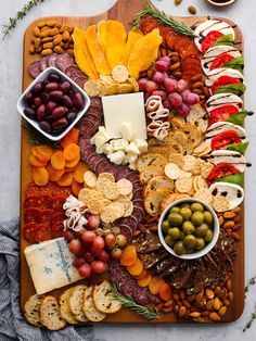 an assortment of cheeses, crackers, grapes and nuts arranged on a platter