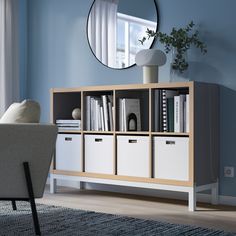 a living room with a chair, mirror and bookshelf on the sideboard