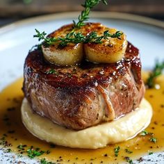 a piece of meat with potatoes and gravy on a white plate, garnished with green sprigs