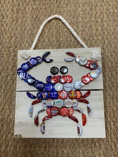 a crab made out of beer bottle caps is hanging on a wooden plank with rope