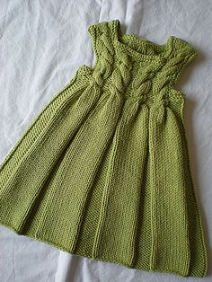 a green knitted dress sitting on top of a bed